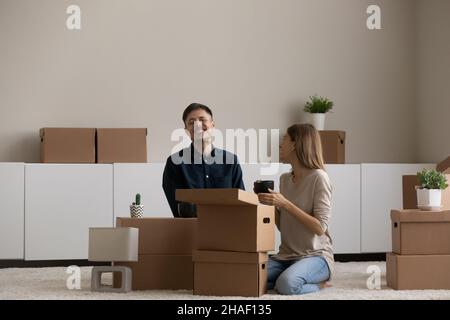 Fröhliches Millennial-Paar genießt Auspacken von Habseligkeiten in eigener Wohnung. Stockfoto