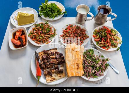 Ciger SIS Kebap in Adana, Türkei. Traditioneller Leberschischkebab im Restaurant. Leberspieße Präsentation mit verschiedenen Salaten, Ayran und Rübe auf t Stockfoto