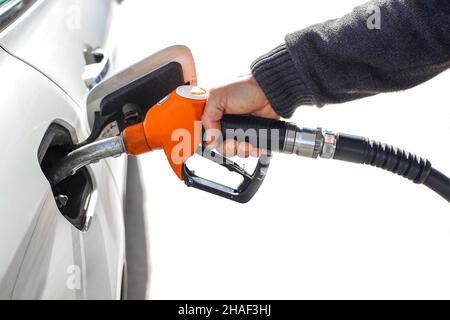 Mann hält Gasschlauch, Benzinpumpendüse isoliert auf weißem Hintergrund. Kraftstoffdüse mit dem Schlauch, der Benzin in ein Auto an einer Tankstelle pumpt. Stockfoto