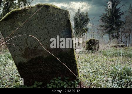 Alte moosige Gräber auf einem verlassenen Friedhof Stockfoto