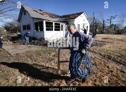 Defiance, Usa. 12th Dez 2021. Ein Freiwilliger sammelt Müll in der Nähe eines beschädigten Hauses, das am Sonntag, dem 12. Dezember 2021, von einem mächtigen Tornado in Defiance, Missouri, zerstört wurde. Am Freitag, den 10. Dezember 2021, traf ein Tornado die kleine Stadt westlich von St. Louis, zerstörte 25 Häuser und tötete eines. Foto von Bill Greenblatt/UPI Credit: UPI/Alamy Live News Stockfoto