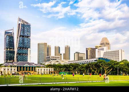 Fußballaktivitäten auf dem Padang Field, mit Singapore Recreation Club, Suntec City und Hotels im Hintergrund. Stockfoto