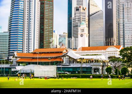 Fußballaktivitäten auf dem Padang Field, mit Singapore Cricket Club im Hintergrund Stockfoto