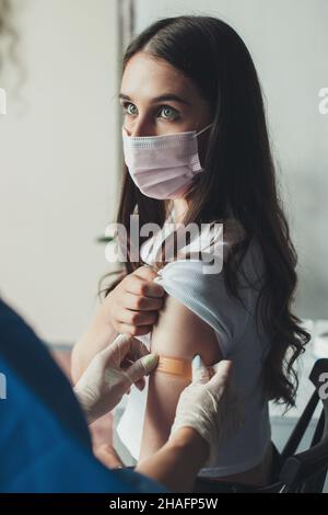 Arzt, der nach der Injektionsimpfung einen Pflaster-Verband auf einen Patientenarm legt. Impfungen für Erwachsene, Covid-Impfstoff. Gesundheitswesen, Coronavirus. Gesund Stockfoto