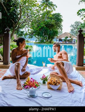 Das Paar frühstückte vor ihrem Zimmer am Pool in Thailand. Mann und Frau mittleren Alters im Urlaub beim Frühstück am Pool gerade mit Kaffee aufwachen Stockfoto