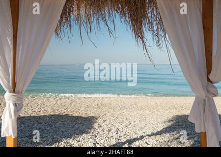 Himmelbett mit weißen Vorhängen am Sandstrand