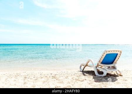 Eine einone, weiß blaue Sonnenliege steht direkt am Wasser an der Küste. Das Konzept eines Strandurlaubs am Meer oder Meer. Privater Strand des Hotels. Ruhige, ruhige Meerseite. Hochwertige Fotos Stockfoto