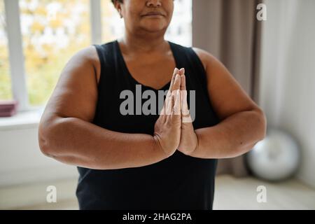 Nahaufnahme einer schwarzen älteren Frau, die während des Yoga in Innenräumen meditiert, konzentrieren Sie sich auf die Hände in Balance Stockfoto