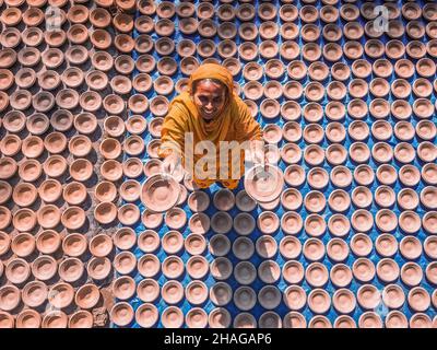 Bogura, Rajshahi, Bangladesch. 13th Dez 2021. Die Arbeiterinnen stellen Töpferwaren her, um sie auf einem Markt zu verkaufen.die Arbeiter sammeln Ton aus dem Boden, bevor sie ihn mit den Händen Formen, in der Sonne trocknen und schließlich die fertige Töpferei bemalen. (Bild: © Mustasinur Rahman Alvi/ZUMA Press Wire) Stockfoto