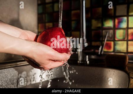 Weibliche Hände waschen Apfel unter Wasser im Waschbecken Stockfoto