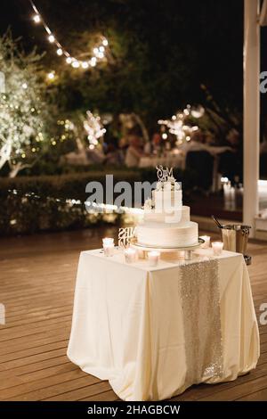 Dreistufiger Hochzeitstorte, geschmückt mit Blumen auf einem Tisch mit Tischdecke Stockfoto
