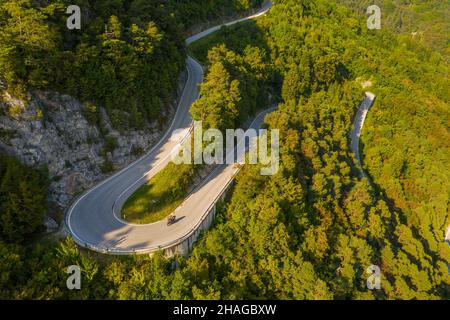 Luftaufnahme der Straße (SP53), die sich durch den Wald oberhalb der Stadt Preore in der Region Trentino in Italien schlängelt Stockfoto