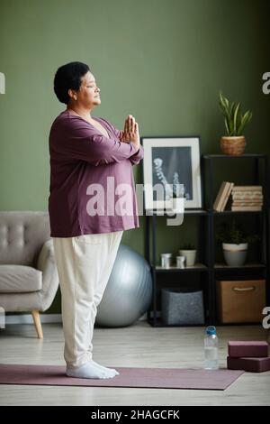 Seitenansicht Porträt einer aktiven älteren Frau, die zu Hause Yoga macht und Balance übt Stockfoto