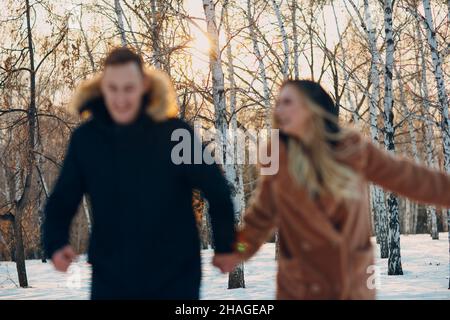 Liebevolles junges Paar, das im Winterwaldpark spielt und Spaß hat. Stockfoto