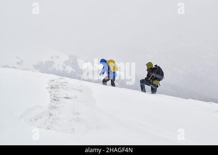 Winterwanderer, die von einem schlechten Wetter in einem tiefen Schnee in den Bergen gefangen sind Stockfoto