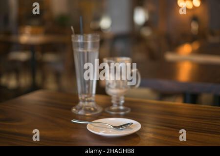 Zwei leere Eisbecher aus Kaffeeglas auf dem Tisch im Café und eine weiße Untertasse mit einem Löffel. Hochwertige Fotos Stockfoto