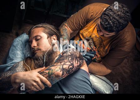 Tattoo-Spezialist zeigt Prozess der Herstellung eines Tattoo in Tattoo-Salon Stockfoto