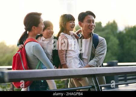 Asiatische Familie mit zwei Kindern, die auf einer Fußgängerbrücke stehen und die Aussicht im Stadtpark genießen Stockfoto