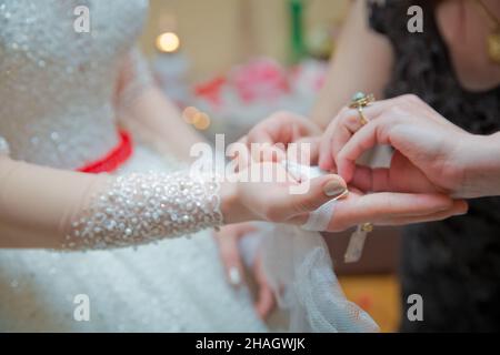 Die Braut legt ihr das Taschentuch in die Hände. Die Hand der Braut ist am Bogen befestigt Stockfoto