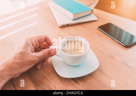 Freiberufler trinkt Kaffee zu Hause im Büro, bevor sie zur Arbeit, Hand halten Tasse, selektive Konzentration Stockfoto