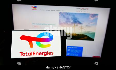 Person, die das Smartphone mit dem Logo des französischen Öl- und Gasunternehmens TotalEnergies SE auf dem Bildschirm vor der Website hält. Konzentrieren Sie sich auf die Telefonanzeige. Stockfoto