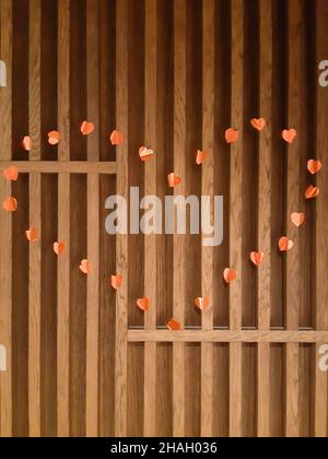 An einer hölzernen Wand aus vertikalen Brettern, die mit einer Herzform aus vielen kleinen roten Herzen ausgekleidet sind Stockfoto