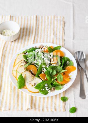 Salat aus Spinat und Quinoa mit Birnen, Orangen und Ricotta. Vorbereitung gesunder Mahlzeiten. Gerichte auf pflanzlicher Basis. Grünes Leben. Veganes Rezept. Styling von Lebensmitteln. Vegetarisch Stockfoto