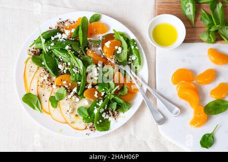 Salat aus Spinat und Quinoa mit Birnen, Orangen und Ricotta. Vorbereitung gesunder Mahlzeiten. Gerichte auf pflanzlicher Basis. Grünes Leben. Veganes Rezept. Styling von Lebensmitteln. Vegetarisch Stockfoto