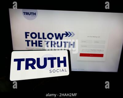 Person, die Mobiltelefon mit dem Logo der US-Medienplattform TRUTH Social (von TMTG) auf dem Bildschirm vor der Webseite hält. Konzentrieren Sie sich auf die Telefonanzeige. Stockfoto