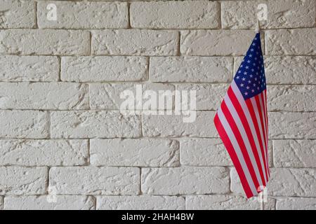 Auf der rechten Seite des Rahmens befindet sich die US-Flagge vor dem Hintergrund einer hellen Ziegelwand. Lassen Sie freien Platz, um Text einzufügen Stockfoto