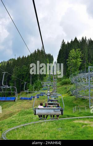 Ein Lift mit vielen Bänken bringt die Menschen auf den mit Bäumen bedeckten Berg. Foto im Sommer, viele Bänke sind leer Stockfoto