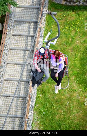 Ein Mann und eine Frau fahren im Sommer mit einem Bergaufzug. Besuchen Sie lokale Sehenswürdigkeiten. Von oben aus einem hohen Winkel fotografiert Stockfoto