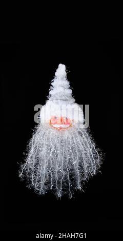 Weihnachtsdekoration in Form des Kopfes des Weihnachtsmannes auf schwarzem Hintergrund. Stockfoto