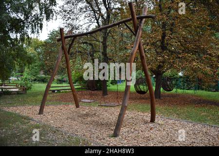 Dekorative große hölzerne Schaukel für zwei Plätze auf dem Hintergrund eines Sommerparks zur Erholung Stockfoto