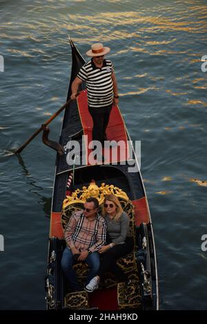 Eine Gondel in Venedig schwebt den Kanal hinunter. Es gibt ein Ehepaar von Touristen und einen Gondoliere. Von oben fotografiert Stockfoto