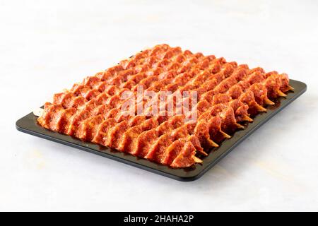 Würziger, roher adana Kebab auf weißem Holzhintergrund. Stockfoto