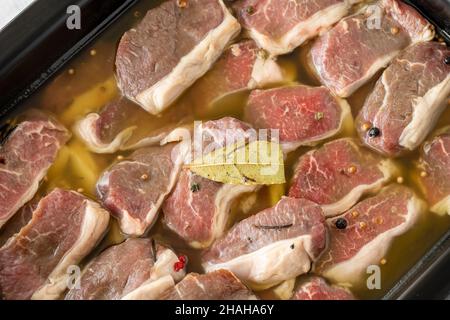 Mariniertes, knochenloses Lammfleisch auf weißem Holzhintergrund. Fleisch Hintergrund. Nahaufnahme von Fleischstücken Stockfoto