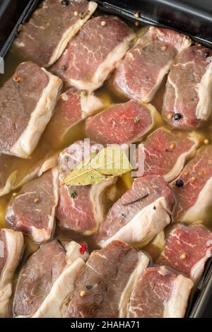 Mariniertes, knochenloses Lammfleisch auf weißem Holzhintergrund. Fleisch Hintergrund. Nahaufnahme von Fleischstücken Stockfoto