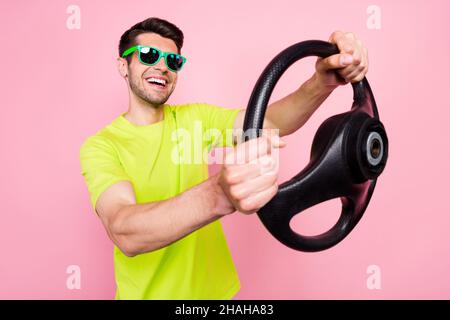 Foto Porträt lächelnder Mann trägt helle T-Shirt Sonnenglas halten Lenkrad lachen glücklich isoliert rosa Farbe Hintergrund Stockfoto