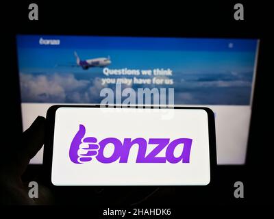 Person, die Mobiltelefon mit dem Logo der australischen Fluggesellschaft Bonza Aviation Pty Ltd. Auf dem Bildschirm vor der Webseite des Unternehmens hält. Konzentrieren Sie sich auf die Telefonanzeige. Stockfoto