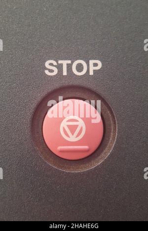 Close-up-STOPP-Knopf in rot mit einer Aufschrift darüber und einem speziellen Symbol darauf angebracht. Auf einem wellig dunklen Hintergrund Stockfoto