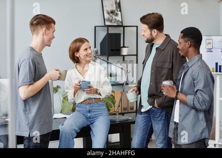 Eine Gruppe junger Mitarbeiter diskutiert Arbeitsmomente während des Kaffeetrinkens während der Kaffeepause Stockfoto
