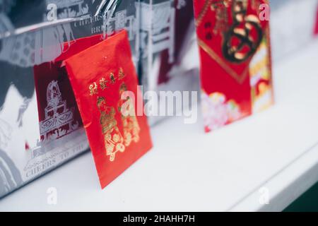 Aufrechter roter Umschlag oder rotes Paket namens Ang Pao oder Ang Pow, auch Hongbao oder Hungbao auf Mandarin und Lai auf Kantonesisch auf weißem Tisch. Stockfoto