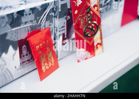 Aufrechter roter Umschlag oder rotes Paket namens Ang Pao oder Ang Pow, auch Hongbao oder Hungbao auf Mandarin und Lai auf Kantonesisch auf weißem Tisch. Stockfoto