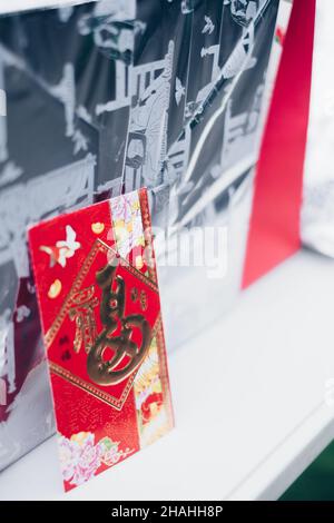 Aufrechter roter Umschlag oder rotes Paket namens Ang Pao oder Ang Pow, auch Hongbao oder Hungbao auf Mandarin und Lai auf Kantonesisch auf weißem Tisch. Stockfoto