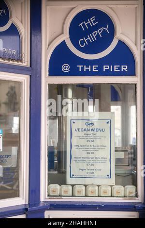 Ein veganes Menü außerhalb eines Fish-n-Chip-Shops, das auf die Nachfrage nach veganem und vegetarischem Essen auf dem Eastbourne Pier in East Sussex, Großbritannien, angepickt ist. Stockfoto