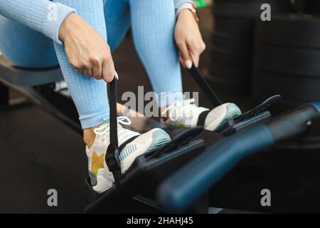 Frau bereitet sich auf Ruderübungen vor. Mädchen sitzt auf einem Rudergerät Stockfoto