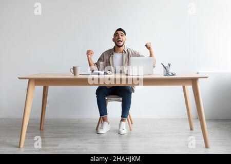 Arabischer Mann mit Laptop feiert Erfolg Schütteln Fäuste schreiend ja Stockfoto