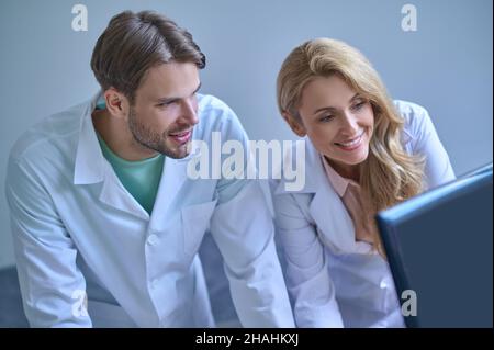 Mann und Frau im weißen Mantel, die auf den Computer schauen Stockfoto