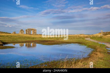 Die Ruinen der St. Dwynwen Kirche spiegeln sich im Wasser auf Llanddwyn Island, Isle of Anglesey, Nordwales Stockfoto